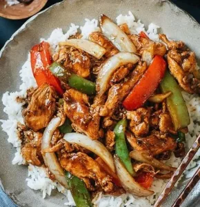 Plate of savory black pepper chicken with vegetables and rice